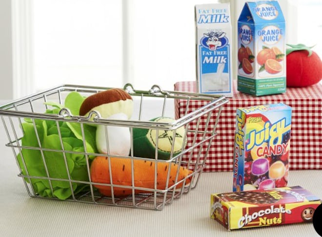 Image of a kid's toy grocery set, with metal shopping basket, fabric foods and boxed grocery items.