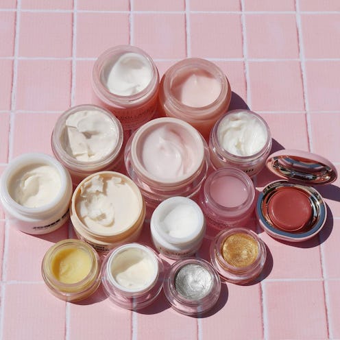 open jars of beauty products on pink tile