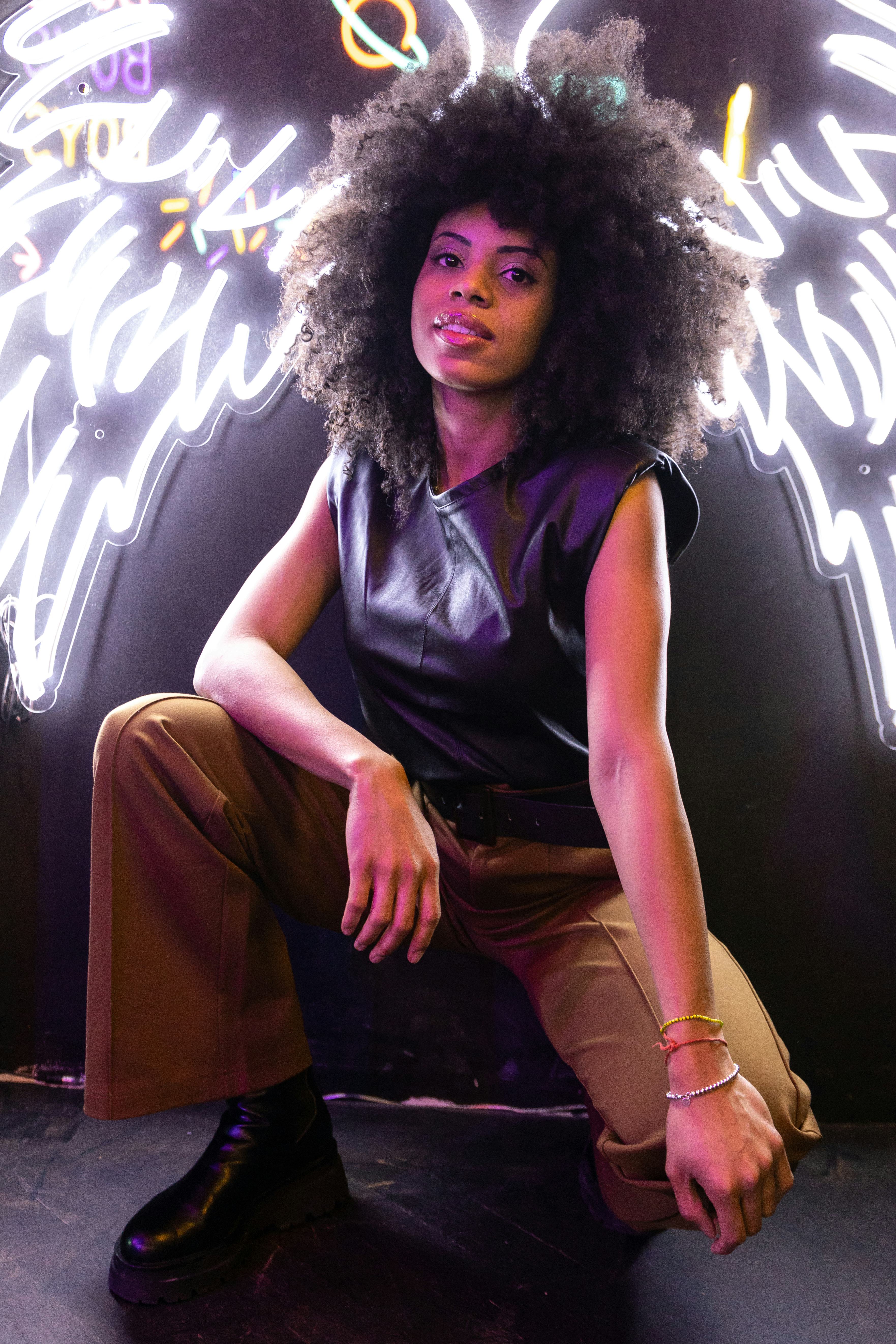 Young woman crouching in front of neon lights to show how Scorpio season 2021 ending will affect her...