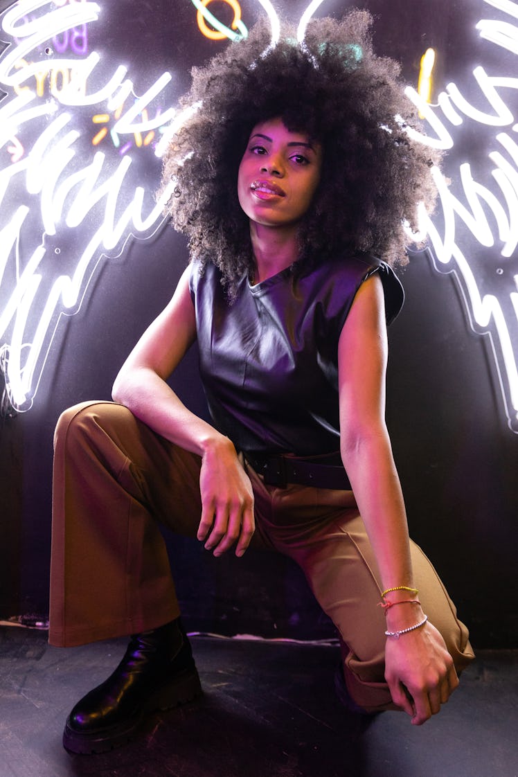 Young woman crouching in front of neon lights to show how Scorpio season 2021 ending will affect her...