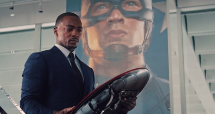 Sam wilson holding captain americas shield as a picture of captain america hands behind him