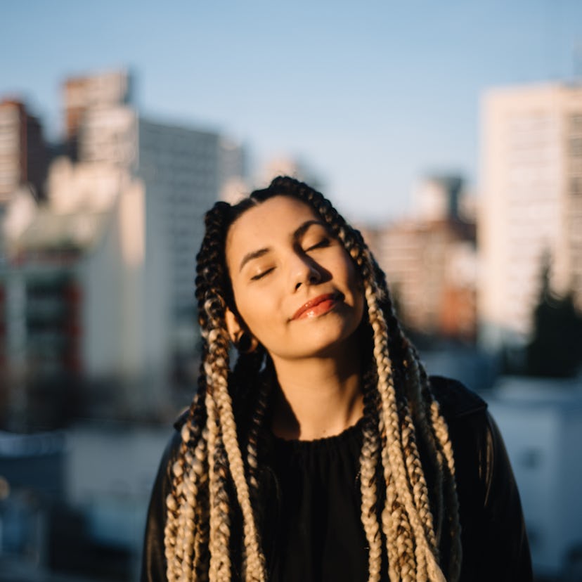 Young woman in standing against a city background, having the best Sagittarius season 2021, per her ...