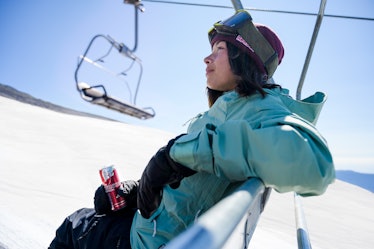 Olympic snowboarder Hailey Langland as seen in profile on a ski lift, holding a can of Red Bull.