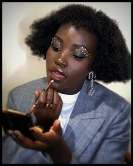 Lupita Nyong'o applying makeup with rhinestones