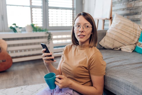 Woman sitting on the ground with her phone.