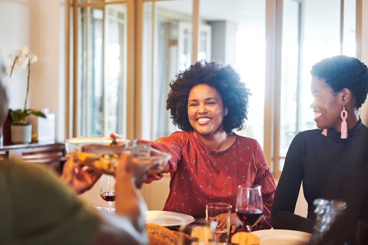 Young woman smiling over the food at dinner, in need of turkey puns and Thanksgiving puns for Instag...