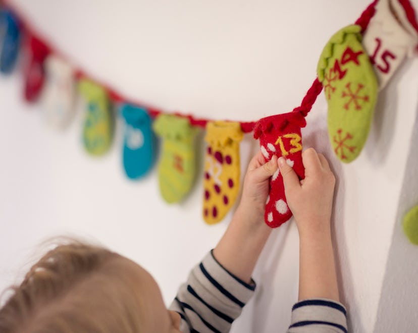 A child opens day 13 in a Christmas Countdown calendar.