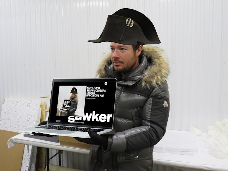 Bryan Goldberg wearing Napoleons hat while holding a laptop with his picture on it.