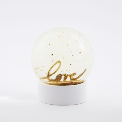 Snow globe with white base and the word "love" in gold inside the globe