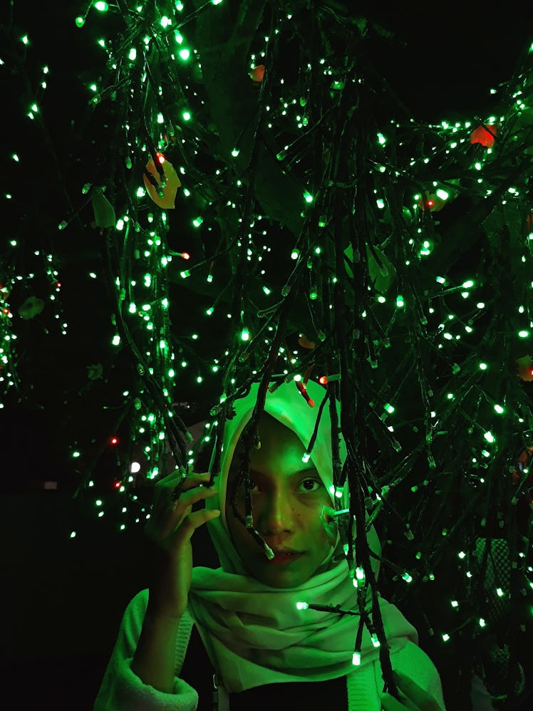 Young woman illuminated by Christmas lights, waiting to hear the Christmas 2021 horoscope for her zo...