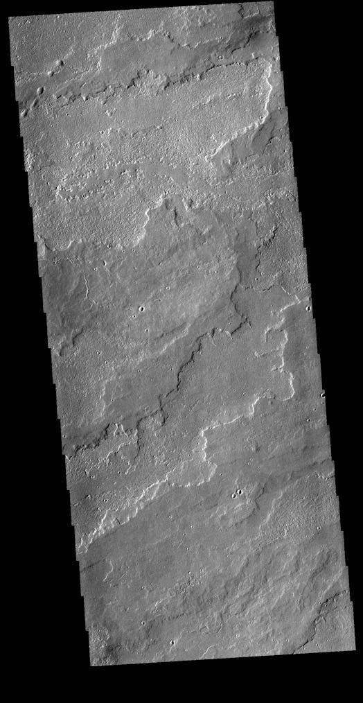 The image shows a portion of the immense volcanic flow fields in the Tharsis region. 
