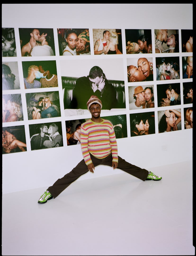 Tyrell Hampton posing in front of a wall full of photos