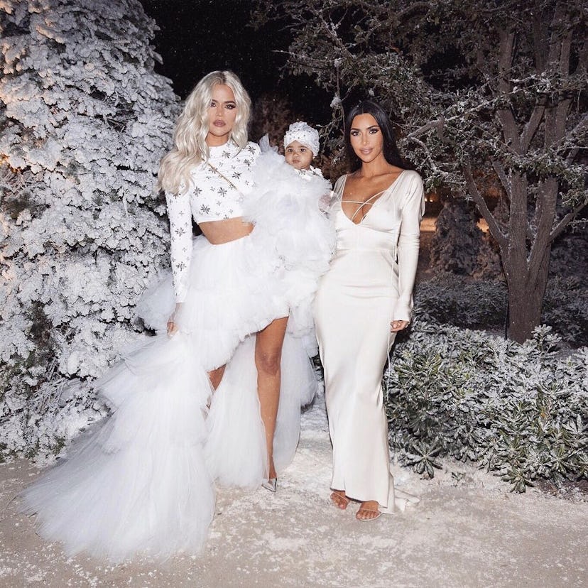 Kim, Khloe, and her baby posing for a photo in white dresses