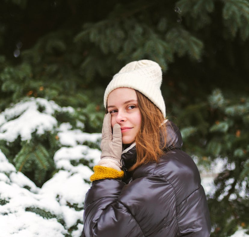 Young woman holding her cheek in the snow amid the 2021 winter solstice with its beautiful spiritual...