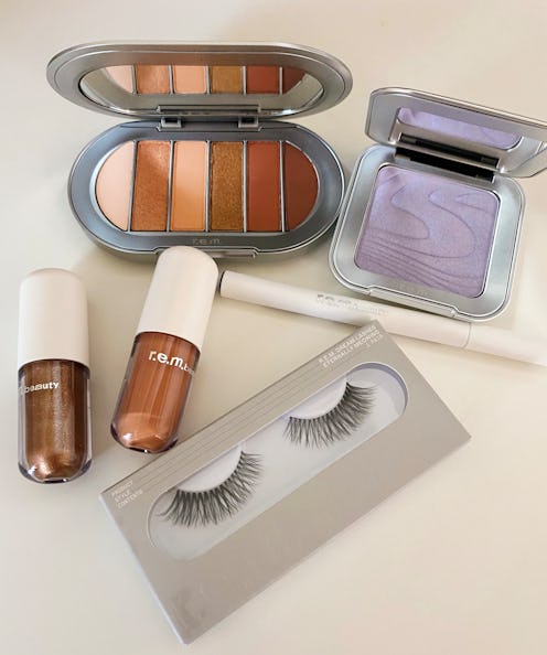 Ariana Grandes makeup collection being displayed on a white table top