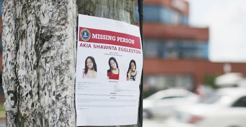 a photograph of a red and white missing persons flyer for Akia Shawnta Eggleston hung on a tree in t...