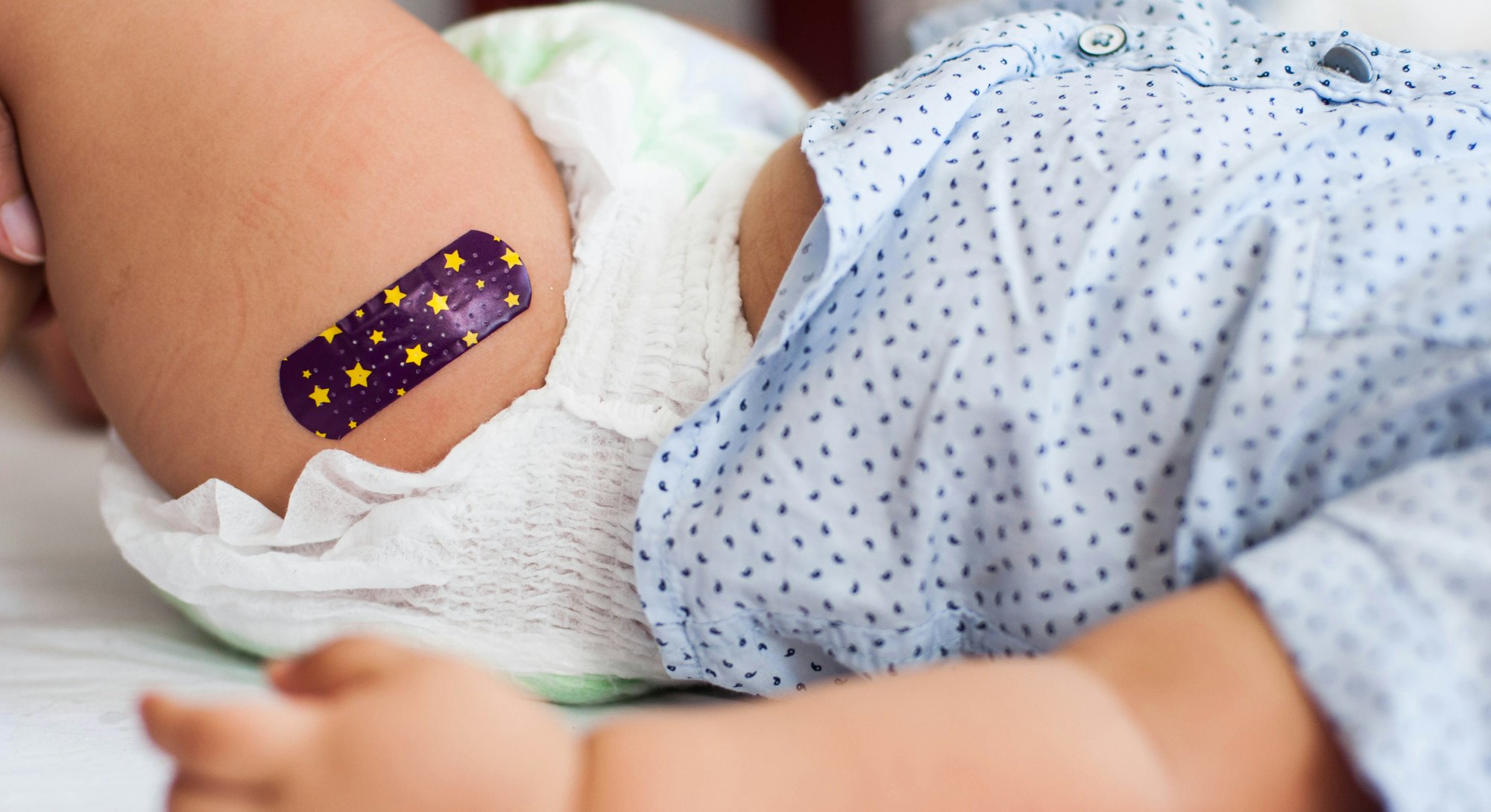 Close-up view of baby boy with Bandaid after vaccination in the medical clinic