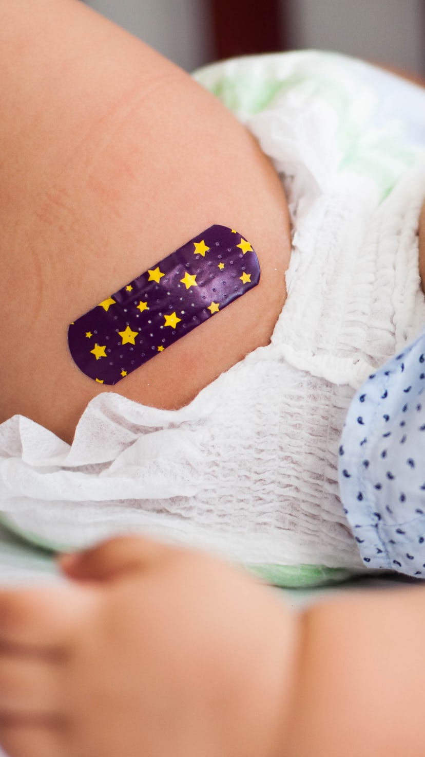 Close-up view of baby boy with Bandaid after vaccination in the medical clinic