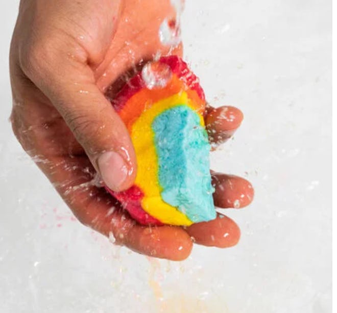 Hand holding a rainbow bubble bar under water faucet