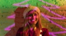 Young woman smiling with a neon tree outline in the background, having the best Christmas 2021, per ...