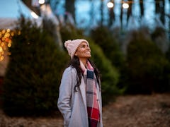 Young woman shopping on a Christmas tree farm before posting on Instagram with a fun quote, lyric, c...