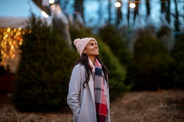 Young woman shopping on a Christmas tree farm before posting on Instagram with a fun quote, lyric, c...