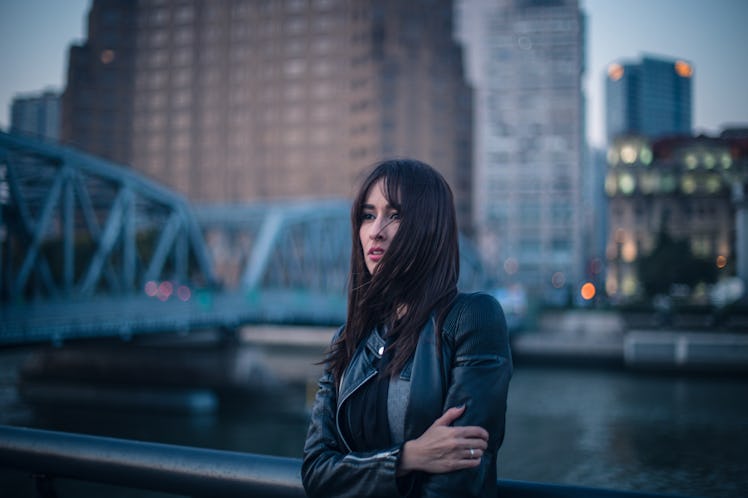 Young woman standing next to river while wearing a leather jacket, thinking about how January 2022 w...