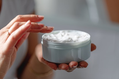 woman holding a jar of face cream