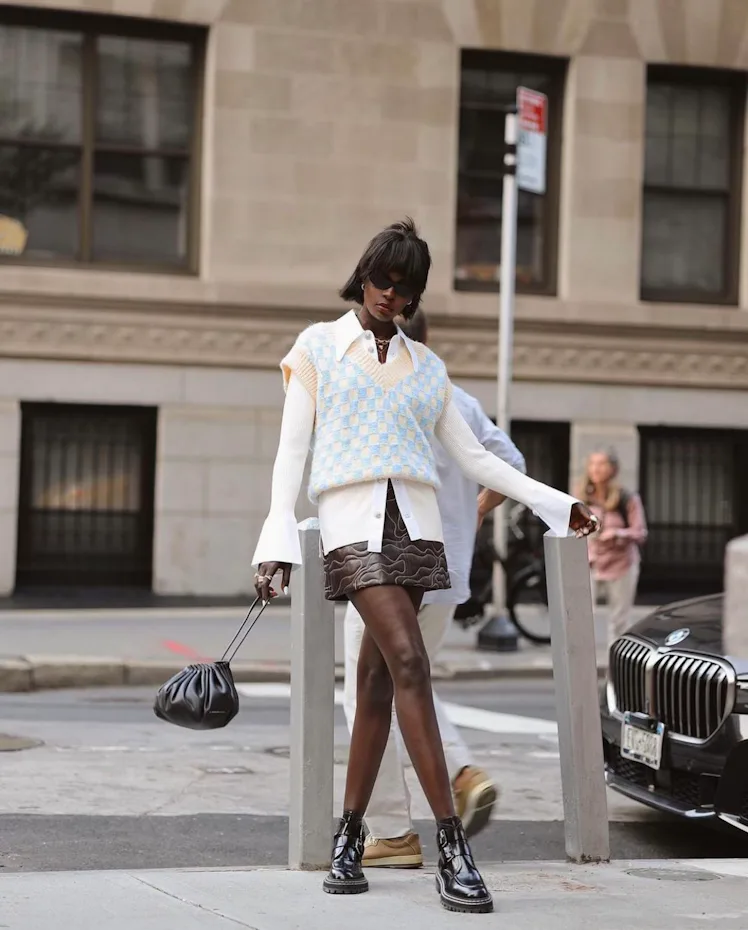 An influencer wearing a leather skirt from GANNI.