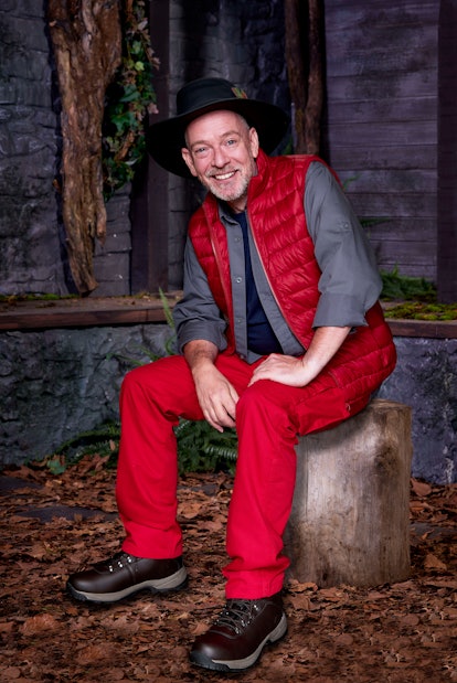 Adam Woodyatt AKA Ian Beale dressed in his red, grey and navy camp clothes with brown hiking boots