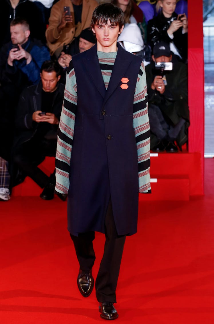 A male model walking in a sleeveless coat