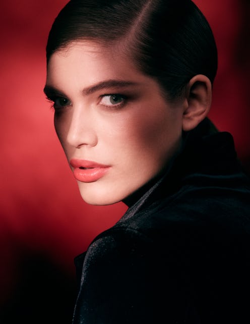 Model Valentina Sampaio in a side-profile shot in a black top with red background