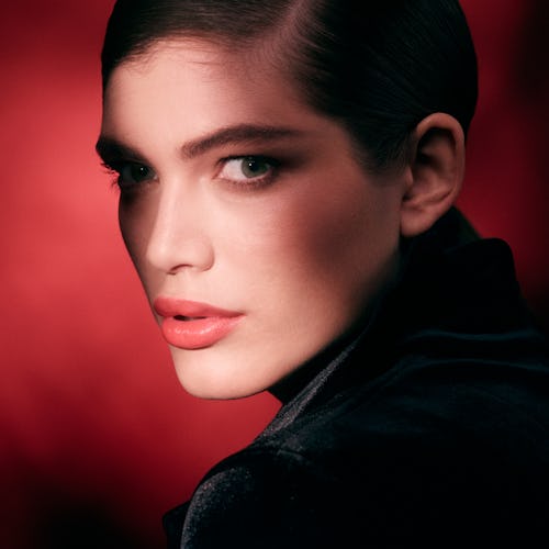 Model Valentina Sampaio in a side-profile shot in a black top with red background