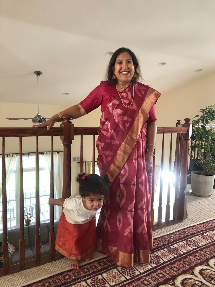 The author in a red and gold sari, with her toddler, celebrating Durga Puja and her daughter’s secon...