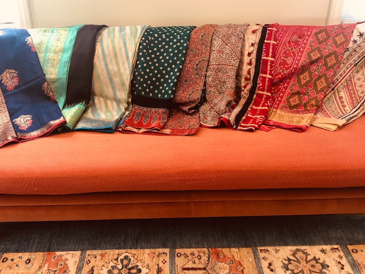 Saris displayed on the back of a burnt-orange couch