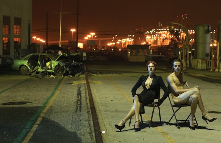 two models in folding chairs on a dark street