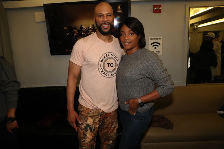 Common in a white shirt and camo pants and Tiffany Haddish in a grey sweater and blue denim jeans