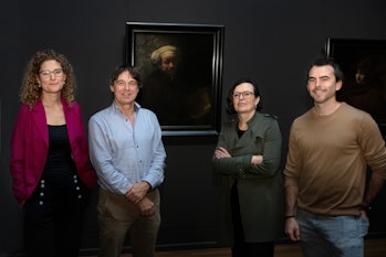 scientists standing in front of a Dutch painting Rembrandt