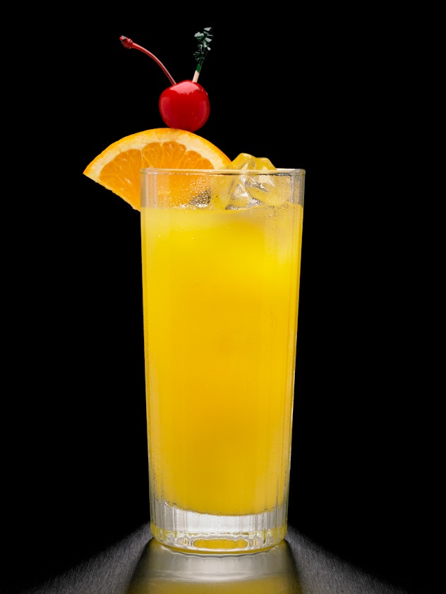 Tall glass with orange juice and fruit garnishes