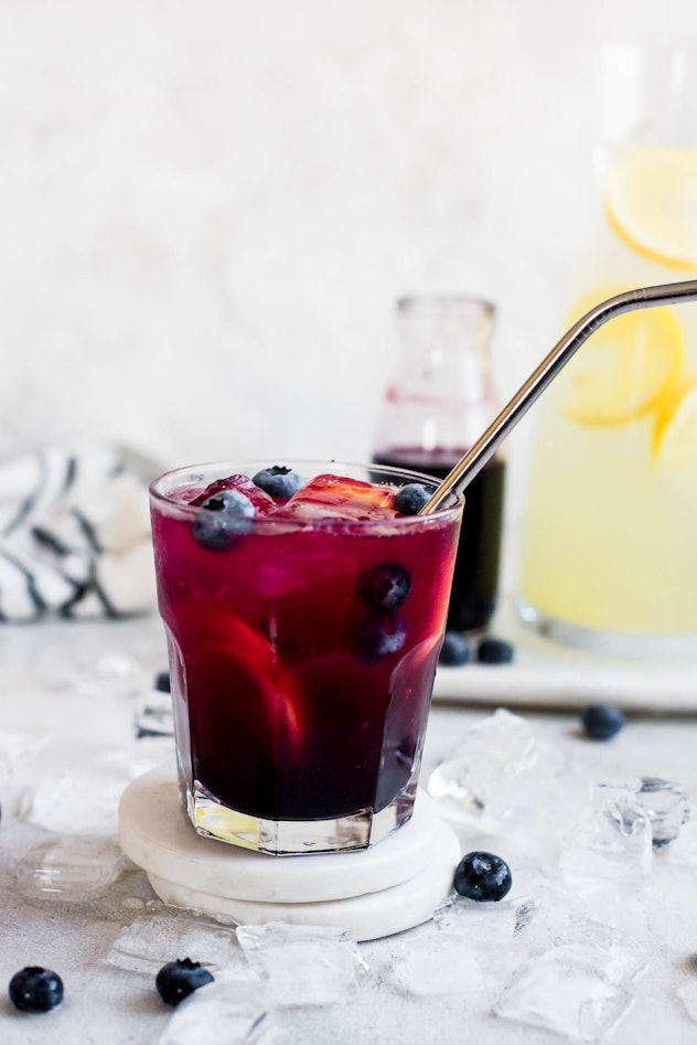 Cocktail glass with blueberry lemonade, with a metal straw sticking out