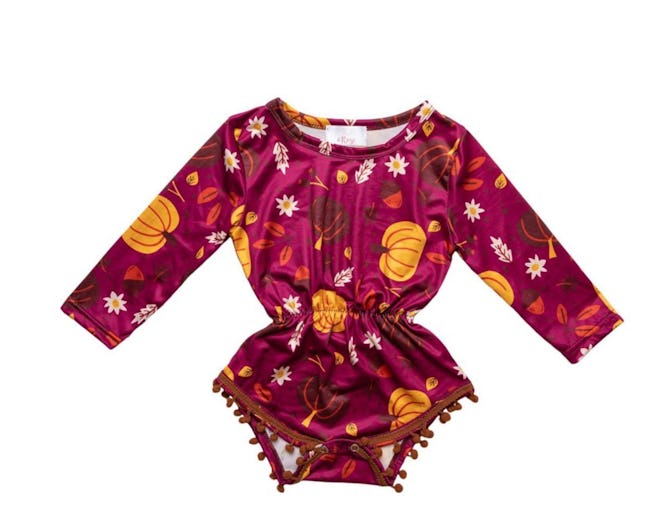 Image of burgundy baby onesie with pumpkin print. Design includes long sleeves and cinched waist.