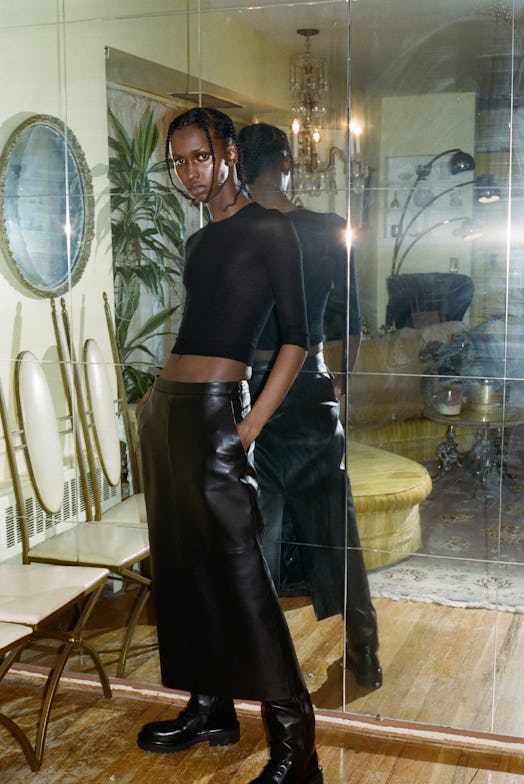 A model in a black crop top and black leather skirt by Altu