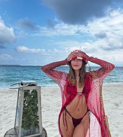 Hailey Bieber wearing a Gonza bikini, knit bucket hat, a Frasier Sterling necklace, and a printed co...