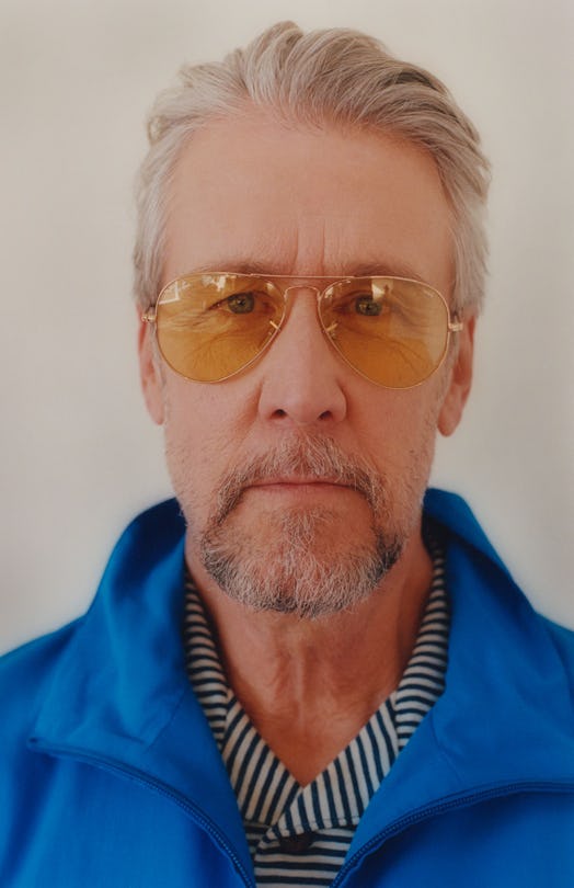 A closeup of Alan Ruck in a blue jacket, stripy shirt and orange sunglasses 