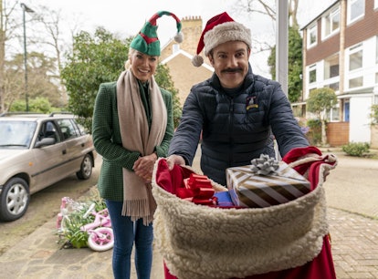 Ted Lasso and Rebecca Welton walk down the street in the Christmas episode of 'Ted Lasso' wearing ug...