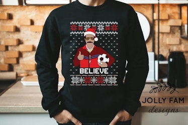 This 'Ted Lasso' ugly Christmas sweater has Ted holding a soccer ball. 