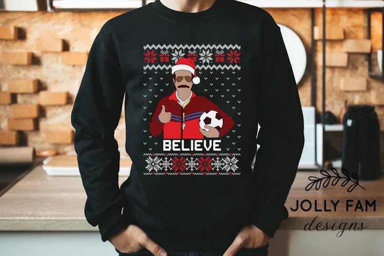 This 'Ted Lasso' ugly Christmas sweater has Ted holding a soccer ball. 
