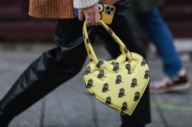 A woman walking and carrying a yellow heart-shaped bag