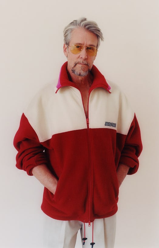 Alan Ruck in a white and red fleece jacket, white khakis and orange sunglasses 