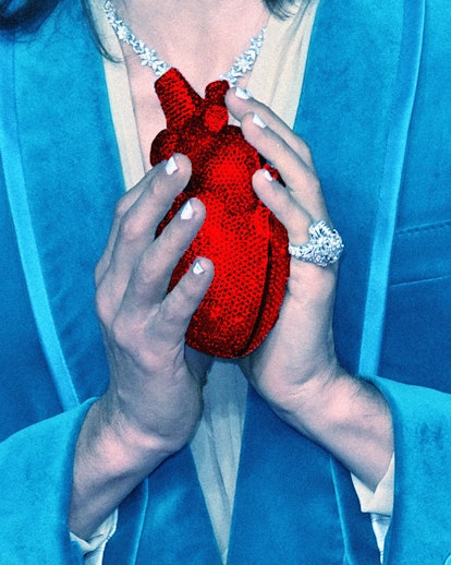Man in a blue tuxedo holding a small red heart-shaped bag